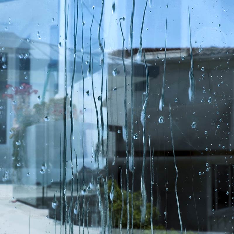 Closeup of Water Drops Beading Down Outdoor Backyard Glass Railing