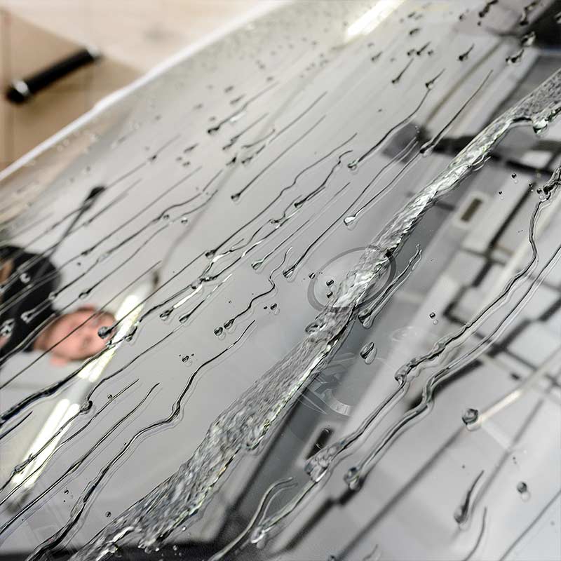 Closeup of Water Running Down a Windshield Treated with the Windshield Defender™ Kit